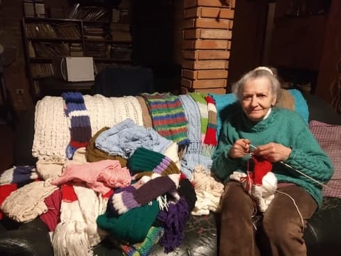 Emilce, una jubilada de 81 años teje bufandas para intercambiarlas por alimentos destinados a ayudar a merenderos de la periferia.